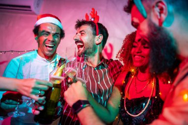 Bir grup neşeli genç arkadaş kadeh kaldırarak eğleniyor ve yılbaşı partisinde şampanya içiyorlar.