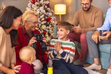 Mutlu çok nesilli aileler Noel 'i evde birlikte geçiriyorlar, çocuklar hediye olarak aldıkları oyuncaklarla oynuyorlar.
