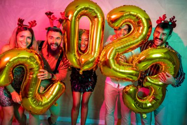 Bir grup genç arkadaş yeni yıl partisinde eğleniyor, dans ediyor ve gece yarısı geri sayımında 2023 numara şeklinde balonlar tutuyor.