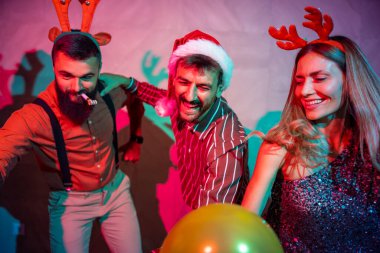 Bir grup neşeli genç arkadaş yeni yıl partisinde dans edip şarkı söylüyor.