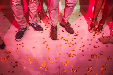 Yılbaşı partisinde yerde bir sürü konfeti ile dans ederken insanların bacaklarının ayrıntıları.