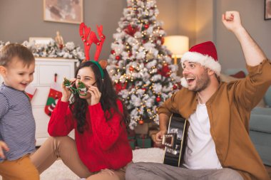 Genç ebeveynler Noel 'i evde yeni yürümeye başlayan çocuklarıyla geçiriyorlar gitar çalıyorlar, Noel şarkıları söylüyorlar ve kış tatilinin tadını çıkarıyorlar.