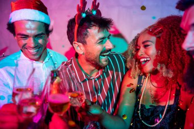 Bir grup neşeli genç arkadaş dans ediyor, kadeh kaldırıyor ve yılbaşı partisinde şampanya içiyor.