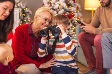 Mutlu çok nesilli aileler Noel 'i evde birlikte geçiriyorlar, çocuklar hediye olarak aldıkları oyuncaklarla oynuyorlar.