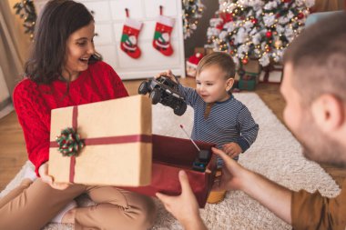 Genç ebeveynler Noel 'i evde yeni yürümeye başlayan çocuklarıyla birlikte geçiriyorlar, hediyeleri açıyorlar ve yeni oyuncaklarla oynuyorlar.