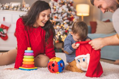 Genç ebeveynler Noel 'i evde birlikte geçirirken küçük çocuklarıyla birlikte Noel hediyelerini açarken eğleniyorlar.