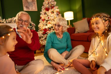 Büyükannem ve büyükbabam Noel arifesini torunlarıyla evde, Noel ağacının yanında oturup Noel ışıklarıyla oynayarak geçiriyorlar.