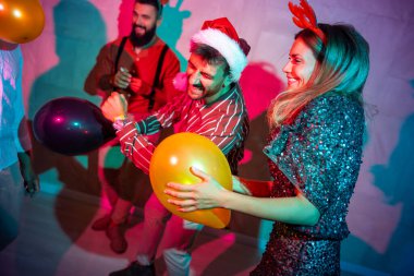 Bir grup neşeli genç arkadaş yeni yıl partisinde dans edip şarkı söylüyor.