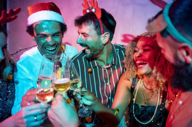 Bir grup neşeli genç arkadaş kadeh kaldırarak eğleniyor ve yılbaşı partisinde şampanya içiyorlar.