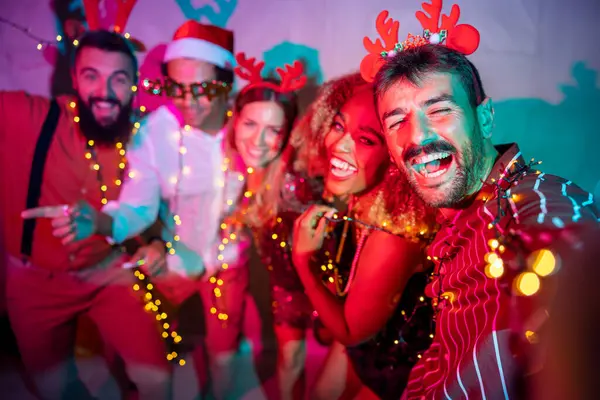 Bir grup neşeli genç arkadaş yeni yıl partisinde selfie çekerken eğleniyorlar.