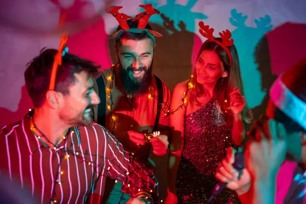 Bir grup neşeli genç arkadaş yeni yıl partisinde şarkı söyleyip dans ediyor.