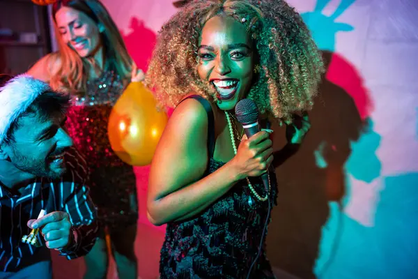 Bir grup neşeli genç arkadaş yeni yıl partisinde karaoke söyleyip dans ederek eğleniyorlar.