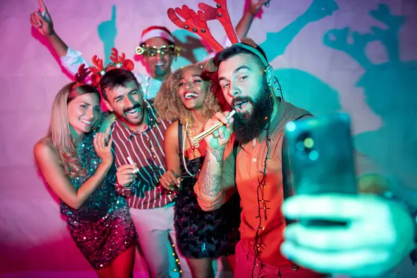 Bir grup neşeli genç arkadaş yeni yıl partisinde selfie çekerken eğleniyorlar.