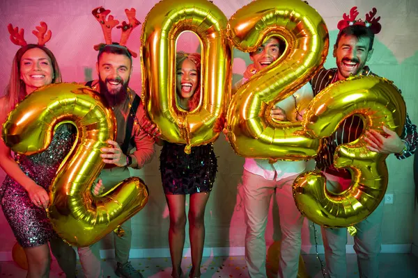 Bir grup genç arkadaş yeni yıl partisinde eğleniyor, dans ediyor ve gece yarısı geri sayımında 2023 numara şeklinde balonlar tutuyor.