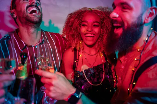 Bir grup neşeli genç arkadaş gece yarısı partisinde dans edip şampanya içerek eğleniyor.