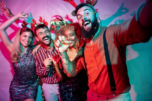 Bir grup neşeli genç arkadaş yeni yıl partisinde selfie çekerken eğleniyorlar.