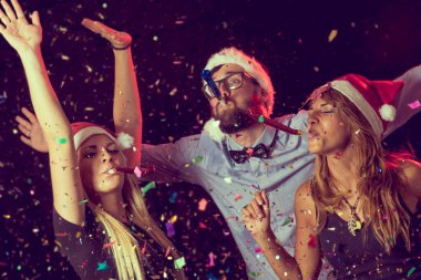 Yılbaşı partisinde üç genç insan ıslık çalıyor.