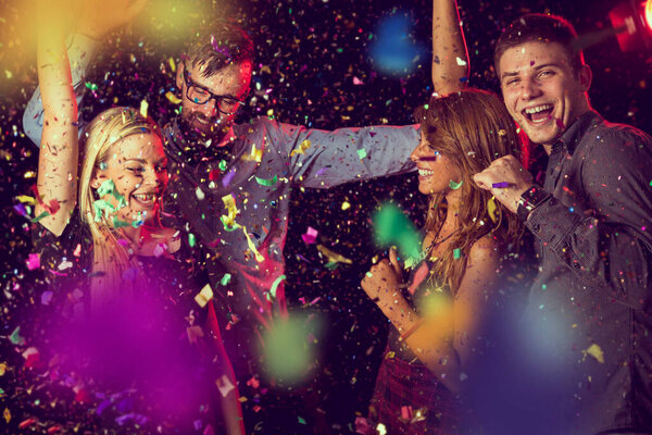 Four young people having fun and dancing at a party