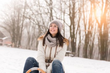 Güzel kız kızakta oturuyor ve karlı bir kış gününün tadını çıkarıyor.