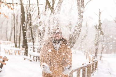 Yakışıklı genç adam güneşli bir kış gününün tadını çıkarıyor ve karda eğleniyor.