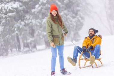 Çiftler kış tatillerini dağlarda geçiriyorlar, karlı bir günü dışarıda geçiriyorlar, kadınlar erkekleri kızakla çekiyor.
