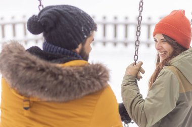 Güzel, genç bir çift, karlı kış günlerini dışarıda, salıncakta oynayarak, dağlarda sallanarak ve eğlenerek geçiriyorlar.