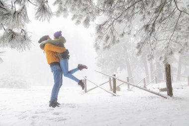 Birbirine aşık çiftler dağlarda karlı bir kış günü geçiriyorlar, erkek arkadaşlar sarılıyorlar ve kız arkadaşlarını kaldırıyorlar.