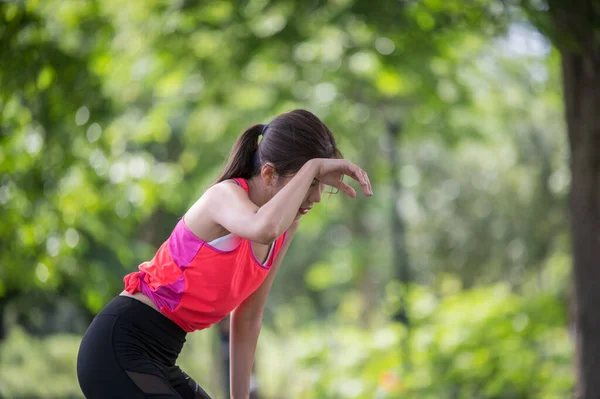 Asian female runner tired after running in the park, Health and lifestyle concept