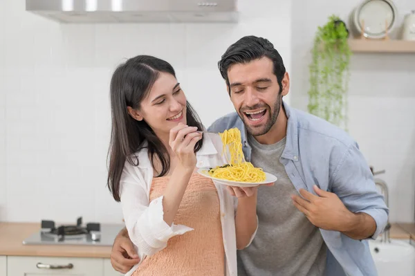 キッチンカウンターで一緒に料理をする幸せな若いカップル家でキッチンでお互いを養う ロイヤリティフリーのストック写真