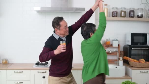 一对快乐的亚洲老夫妻一边跳舞一边笑着在厨房柜台边做饭 — 图库视频影像