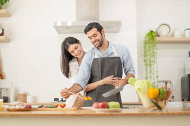 Mutlu çift evde yemek hazırlıyor, genç çift mutfak tezgahında sebze kesiyor, aşık erkek ve kadın.