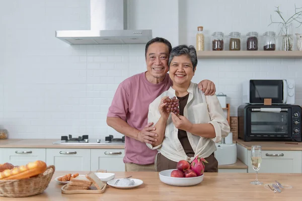 Happy Asian senior eating fruits together in her modern kitchen