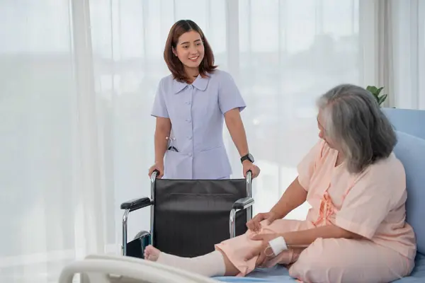 Asian nurse preparing wheelchair for senior female patient at the hospital ward, elderly care concept