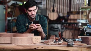 Gitar Luthier küçük işletme sahibi, müşteriden sipariş alan genç adam cep telefonu, sanat ve zanaat konsepti