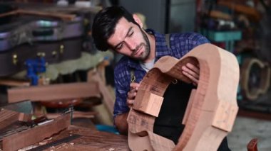 Luthier ahşap müzikal yapıyor ve çalışma odasında el aletleriyle geleneksel aletler kullanıyor.