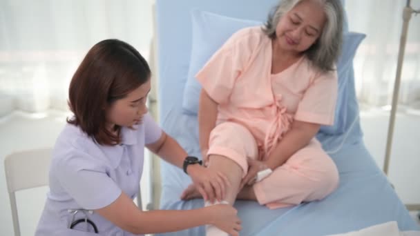 アジアの女性看護師が病院で高齢女性患者の足を包帯 — ストック動画