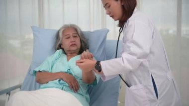 Asyalı kadın hemşire, hastanede veya klinikte yaşlı kadının nabzını ölçer.