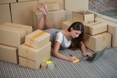 Evde çalışan küçük bir işletme sahibi, müşteriye teslimat siparişi için evdeki adresi yazan bir kadın, online alışveriş işi, ekommerce konsepti.