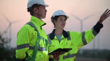 Rüzgar türbini çiftliğinde çalışan ve tablet kullanan mühendisler, rüzgar türbinleri temiz enerji kaynağı, elektrik ve sanayi çevresi için eko teknolojisi üretiyor.