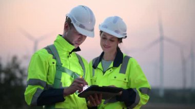 Rüzgar türbini çiftliğinde çalışan ve tablet kullanan mühendisler, rüzgar türbinleri temiz enerji kaynağı, elektrik ve sanayi çevresi için eko teknolojisi üretiyor.