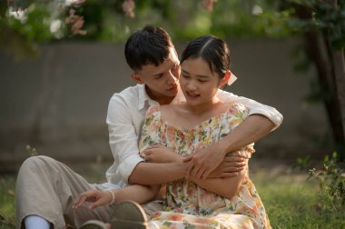 Asyalı genç çift birbirine bakıyor ve sarılıyorlar, erkek ve kadın birlikte vakit geçiriyorlar.