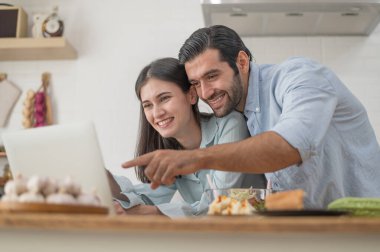 Mutlu çift evde yemek hazırlıyor, genç çift mutfak tezgahında sebze kesiyor, aşık erkek ve kadın.