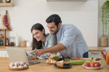 Mutlu çift evde yemek hazırlıyor, genç çift mutfak tezgahında sebze kesiyor, aşık erkek ve kadın.