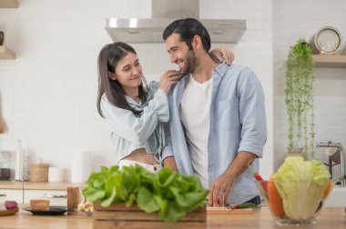Mutlu çift evde yemek hazırlıyor, genç çift mutfak tezgahında sebze kesiyor, aşık erkek ve kadın.