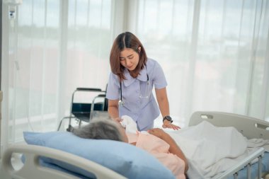 Asyalı hemşireler kadın hastalarla ilgileniyor ve onu hastane koğuşunda teşvik ediyorlar.