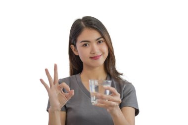 Beyaz arka planda izole edilmiş bir bardak su tutan Asyalı genç kadının portresi.