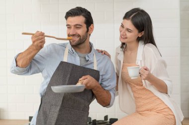 Mutlu genç çift evdeki mutfak tezgahında birlikte yemek pişiriyor.