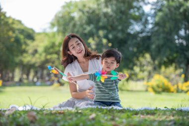 Mutlu Asyalı aile bahçede annesiyle yel değirmeni oynarken eğleniyor.
