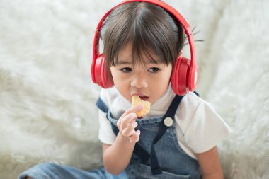 Mutlu Asyalı çocuk portresi kulaklıkla müzik dinlemekten zevk alır.