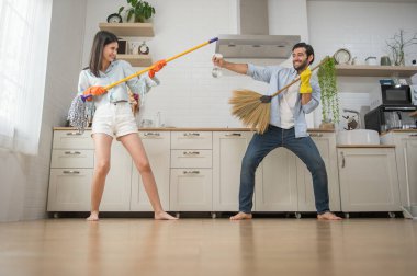 Mutlu çift mutfak temizliği yaparken eğleniyor dans etmek için müzik aletleri yerine süpürge ve paspas kullanıyorlar.